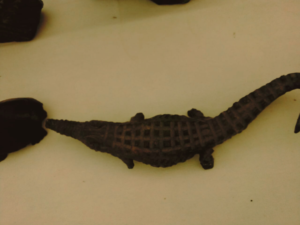 Dark crocodile-shaped object with patterned texture on back, set against a light background.