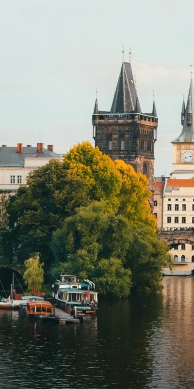 Scenic view of Charles Bridge and historical buildings of Prague at sunset with reflections in the river.
